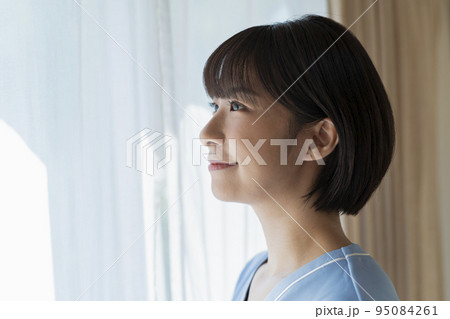 窓際に立つ女性医療従事者 95084261