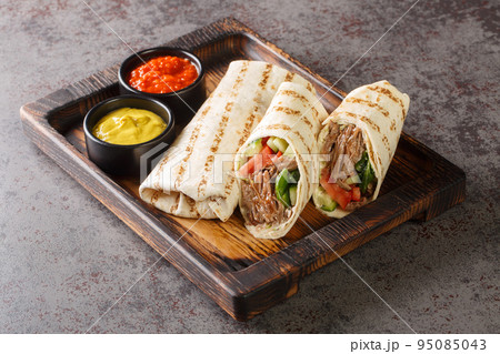 Shawarma sandwich gyro fresh roll of lavash closeup on the wooden board. Horizontal Shawarma sandwich gyro fresh roll of lavash closeup on the wooden board. Horizontal 95085043