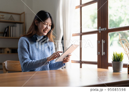 Happy young woman wearing headphone and using digital tablet at home. Happy young woman wearing headphone and using digital tablet at home. 95085598