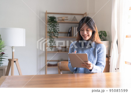 Happy young woman wearing headphone and using digital tablet at home. 95085599