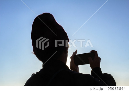 青い空の背景にしたスマホを持つ男性のシルエット 青い空の背景にしたスマホを持つ男性のシルエット 95085844