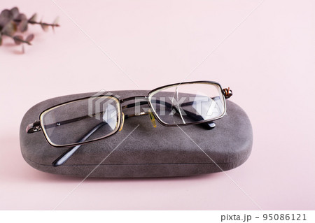 Broken glasses on a hard case on a pink background. The concept of careful storage of optics Broken glasses on a hard case on a pink background. The concept of careful storage of optics 95086121