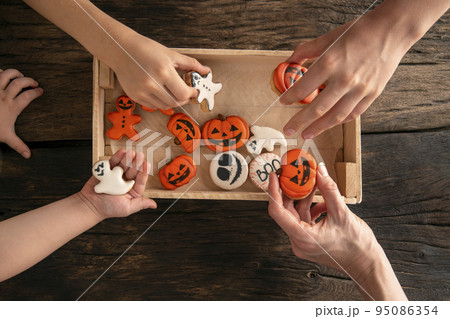 Funny delicious ginger cookies for Halloween on the table. Hands take cookies. Halloween gingerbread cookies in box Funny delicious ginger cookies for Halloween on the table. Hands take cookies. Halloween gingerbread cookies in box 95086354