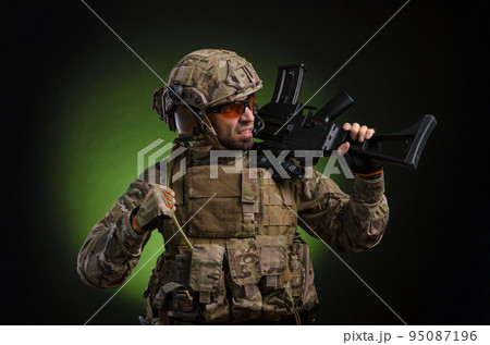a male soldier in military clothes with a weapon on a dark background 95087196