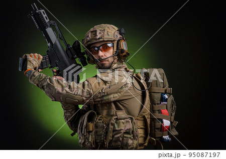 a male soldier in military clothes with a weapon on a dark background a male soldier in military clothes with a weapon on a dark background 95087197