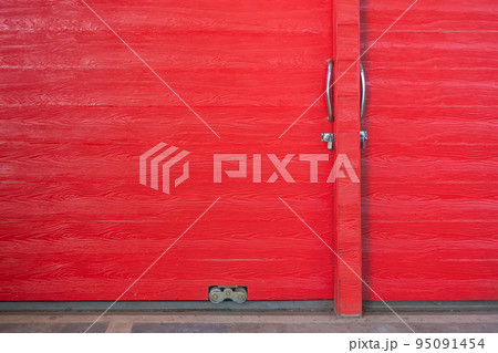 Metal lock and door handle on the red wooden door. Abstract red wood planks background wall texture. Wooden texture red colour for backdrop. Red texture of pine wood grain panel with copy space. 95091454