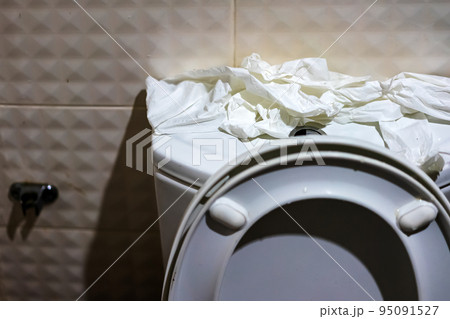 Many of soft toilet paper on top of commode reservoir lid in bathroom. A lot of hygienic paper on flush tank was torn up and prepared to clean up after feces were done. Many tissues on flush toilet. Many of soft toilet paper on top of commode reservoir lid in bathroom. A lot of hygienic paper on flush tank was torn up and prepared to clean up after feces were done. Many tissues on flush toilet. 95091527