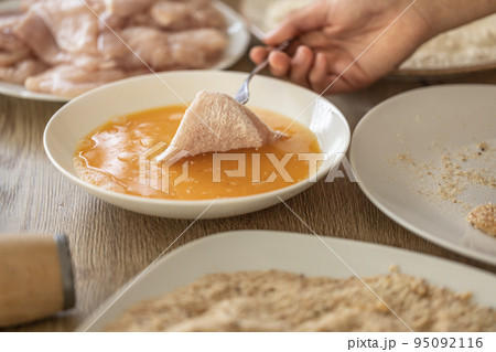 Detail of hand putting chicken meat in flour into eggs during making schnitzels Detail of hand putting chicken meat in flour into eggs during making schnitzels 95092116