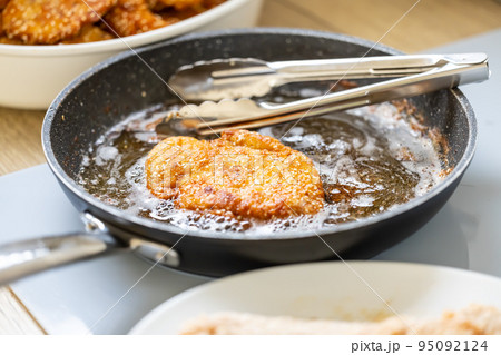 Pan full of oil is used for frying breaded meat while making wiener schnitzels Pan full of oil is used for frying breaded meat while making wiener schnitzels 95092124