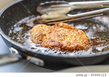 Schnitzel frying in a hot pan finished to golden crispy skin Schnitzel frying in a hot pan finished to golden crispy skin 95092125