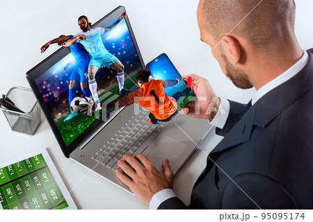 Businessman watches football match and bets on soccer website 95095174