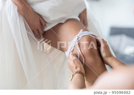 White girdle put on a leg of a bride shortly - Stock Photo