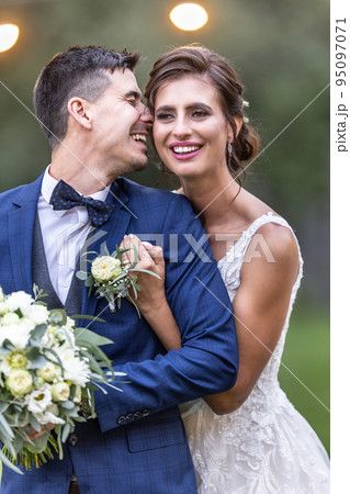 Beautiful newlywed couple laughs and holds each other on their wedding day after the ceremony 95097071
