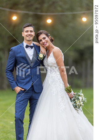 Happy and confident young married couple poses outdoors after saying I do at their wedding 95097072