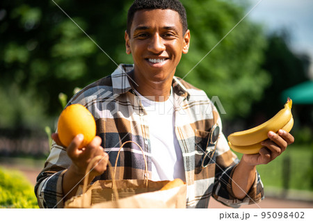 Young man with a paper bag after food shopping 95098402