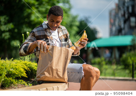 Young man with a paper bag after food shopping Young man with a paper bag after food shopping 95098404