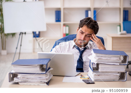 Young male employee and too much work in the office 95100959