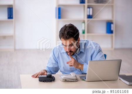 Young male call center operator working at his desk 95101103