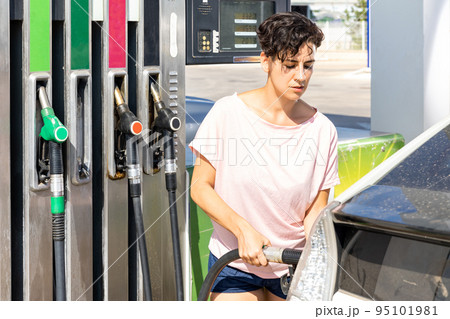 Smiling woman refueling her car in gas station 95101981