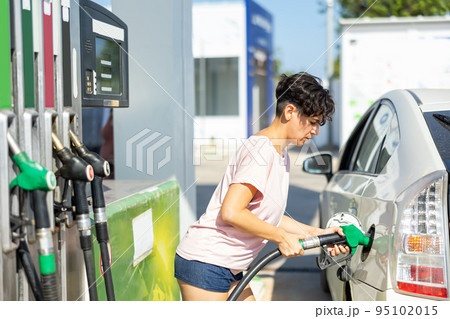 Smiling woman refueling her car in gas station 95102015