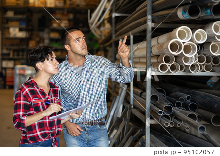 Man and woman working in warehouse, checking documents and poitning finger Man and woman working in warehouse, checking documents and poitning finger 95102057