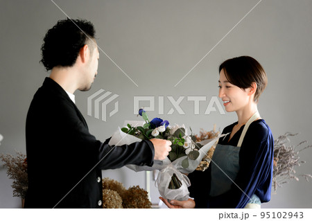 お花屋さんで花束を買いに来る人か奥さんにお花を贈る人 95102943
