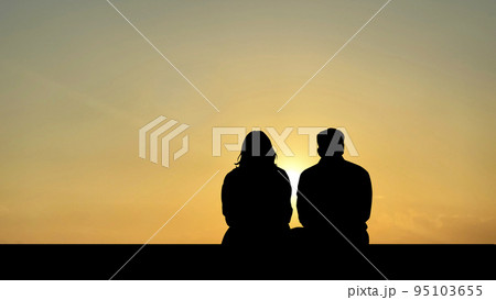 夕日に向かって座った男女シルエット 95103655