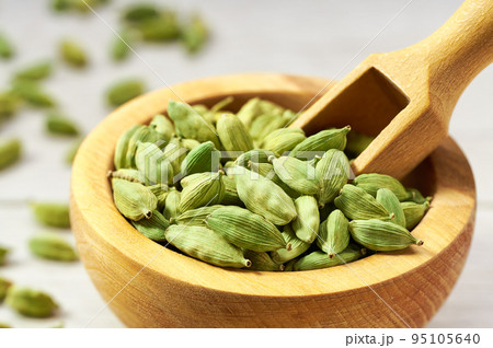 Cardamom pods on a white wooden kitchen table, close up. 95105640