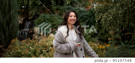 Portrait of pretty asian kazakh brunette woman with charming smile walking along outdoors Portrait of pretty asian kazakh brunette woman with charming smile walking along outdoors 95107548