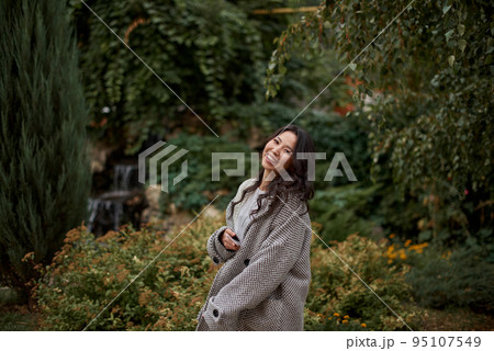 Portrait of pretty asian kazakh brunette woman with charming smile walking along outdoors Portrait of pretty asian kazakh brunette woman with charming smile walking along outdoors 95107549