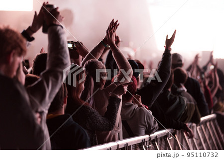 Crowd of people with arms outstretched partying at an EDM concert 95110732