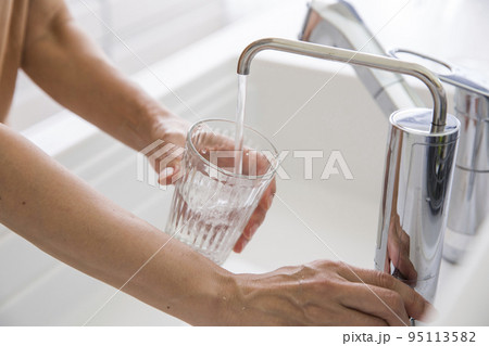 浄水器からコップに水を入れる女性の手元 95113582