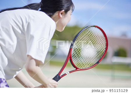 テニスコートでテニスをする若い日本人女性 95115129
