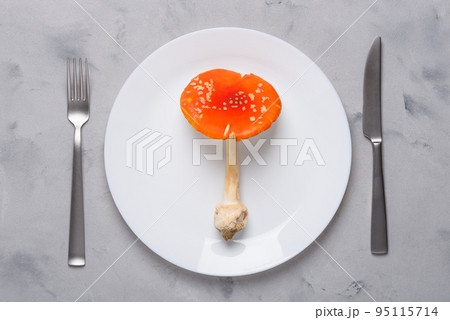 Amanita muscaria fly agaric poisonous mushroom on plate with fork and knife top view. Amanita muscaria fly agaric poisonous mushroom on plate with fork and knife top view. 95115714