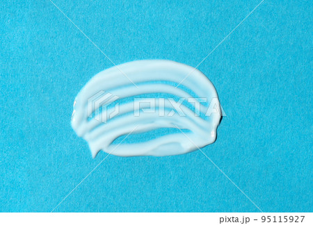 White cream textured sample on blue background. Smear of moisturizer closeup. Top view. Lotion swatch. Beauty, skin care product, smudge drop. SPF ptotection, sunscreen  95115927
