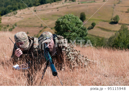 Sniper soldier assisted by an assistant to observe the area to be targeted with modern warfare tactical virtual reality goggles aerial drone military technology. 95115948