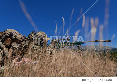 Sniper soldier assisted by an assistant to observe the area to be targeted with modern warfare tactical virtual reality goggles aerial drone military technology. 95116081