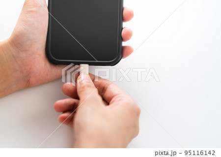スマートフォンを充電する女性の手 95116142