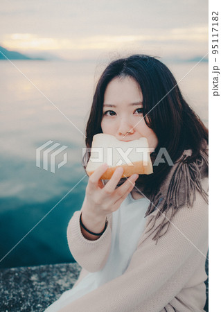 朝焼けが綺麗なパンを食べる女性の写真 朝焼けが綺麗なパンを食べる女性の写真 95117182