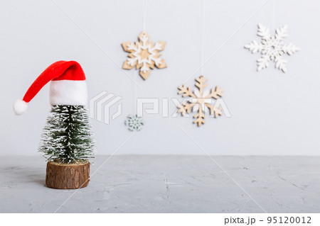 One small Christmas tree with santa hat on colored background. new year decoration with copy space 95120012
