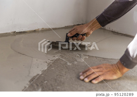 Grey self-leveling screed, new floor layer, man hand. Grey self-leveling screed, new floor layer, man hand. 95120289