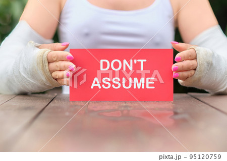DO NOT ASSUME the text on the red card in the hands of a woman with casts on her hands DO NOT ASSUME the text on the red card in the hands of a woman with casts on her hands 95120759