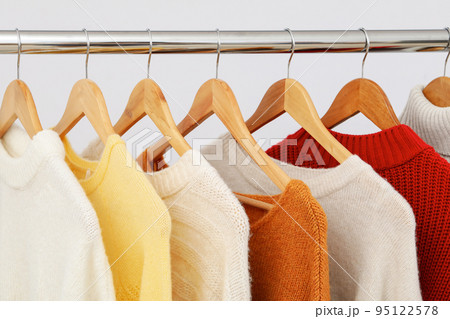 Wardrobe rack with hangers with sweaters on light background 95122578
