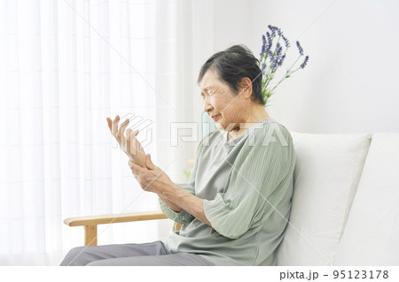 リビングで手が痺れる高齢者女性 リビングで手が痺れる高齢者女性 95123178
