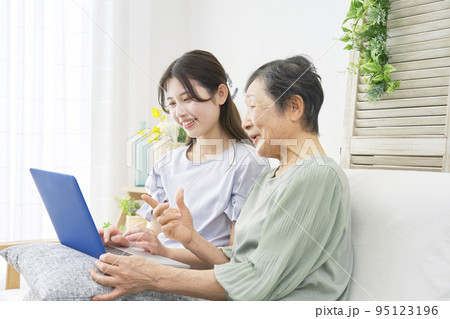 リビングでパソコンを使う孫と祖母 リビングでパソコンを使う孫と祖母 95123196