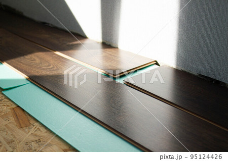 Laminate. Laying brown glossy laminate on the floor of the house. Apartment renovation. Replacing old floor with a new one. Laminate sheets are placed on a wooden base made of pressed sawdust boards 95124426