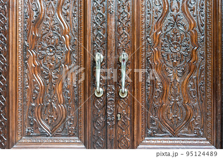 Engraved wooden doors of an old classic cabinet. Antique wooden textures concept. Engraved wooden doors of an old classic cabinet. Antique wooden textures concept. 95124489