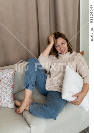 charismatic girl sits on the couch in a comfortable position bend her legs under her charismatic girl sits on the couch in a comfortable position bend her legs under her 95124647