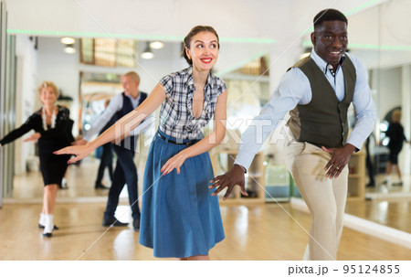 Woman with african man practising charleston dancing Woman with african man practising charleston dancing 95124855