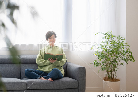 リビングで本を読む若いの女性 リビングで本を読む若いの女性 95125427
